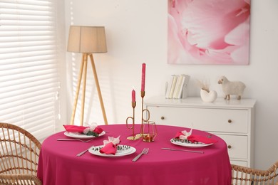 Photo of Beautiful table setting with green branches and burning candles in dining room