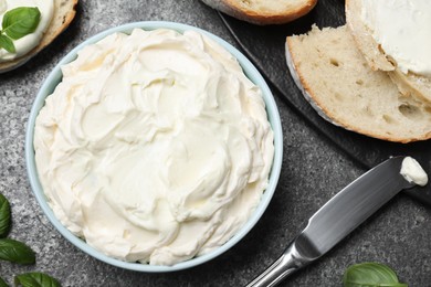 Tasty cream cheese, fresh bread and basil on grey table, flat lay