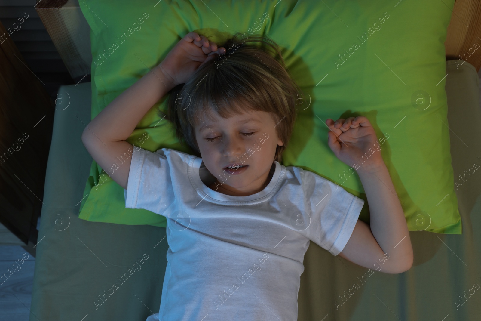 Photo of Little boy snoring while sleeping in bed at night, top view