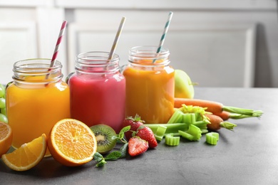 Mason jars with different juices and fresh ingredients on table. Space for text