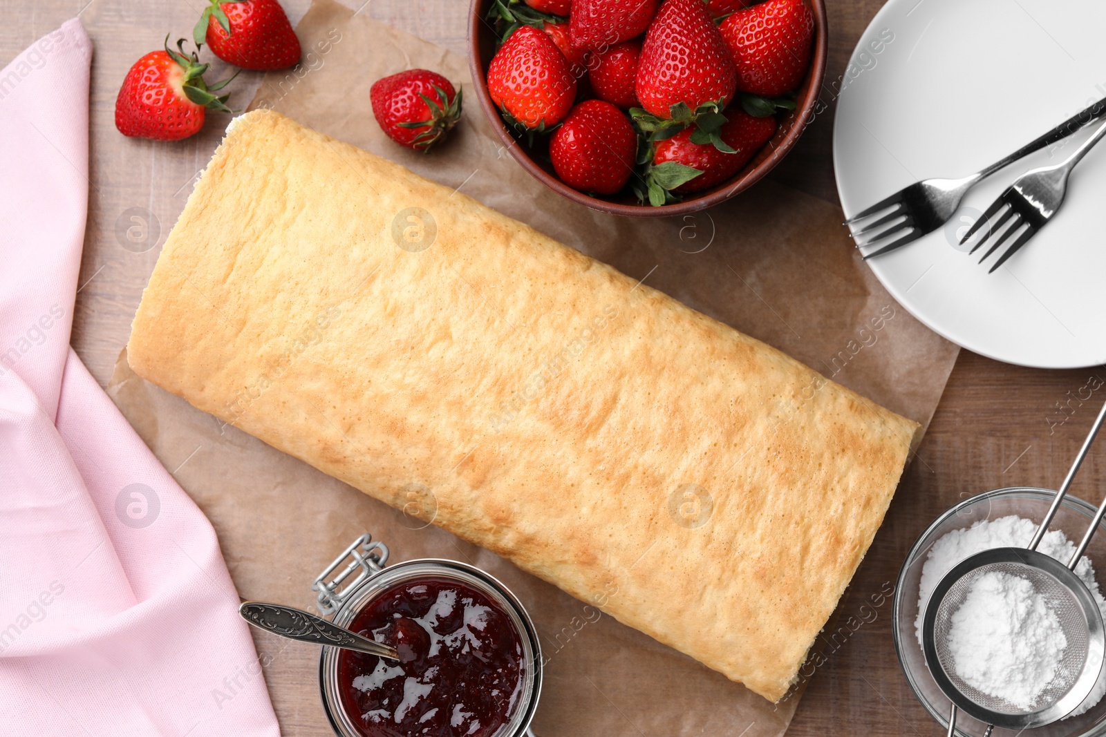 Photo of Delicious sponge cake roll with strawberries on wooden table, flat lay