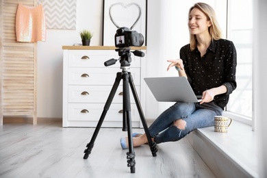 Photo of Young blogger with laptop recording video near window at home