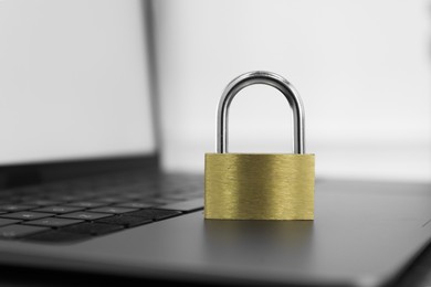 Photo of Cyber security. Metal padlock and laptop on table, closeup