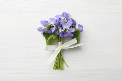 Photo of Beautiful wild violets on white wooden table, top view. Spring flowers