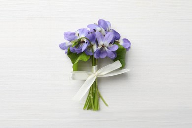 Beautiful wild violets on white wooden table, top view. Spring flowers