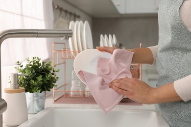 Woman wiping bowl with towel in kitchen, closeup