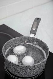 Photo of Boiling chicken eggs in saucepan on electric stove