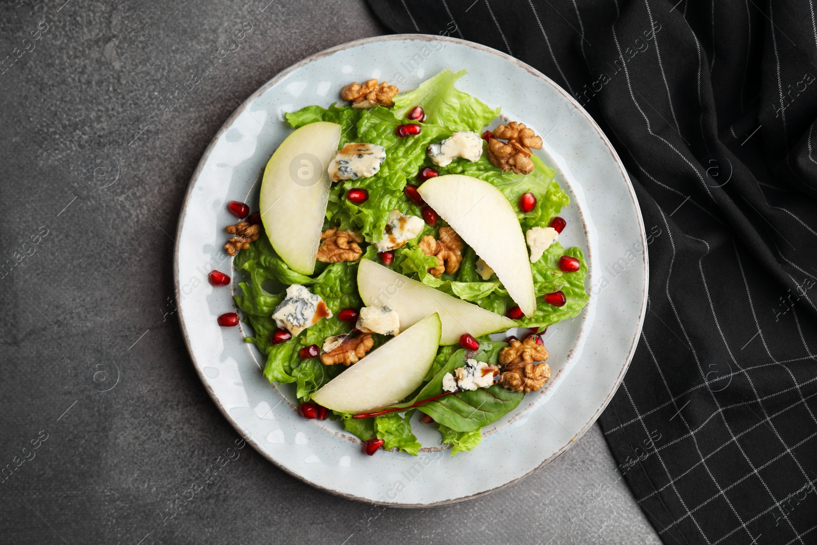 Photo of Delicious pear salad on dark textured table, top view