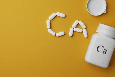 Photo of Calcium supplement pills and jar on yellow background, flat lay. Space for text