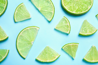 Photo of Juicy fresh lime slices on light blue background, flat lay