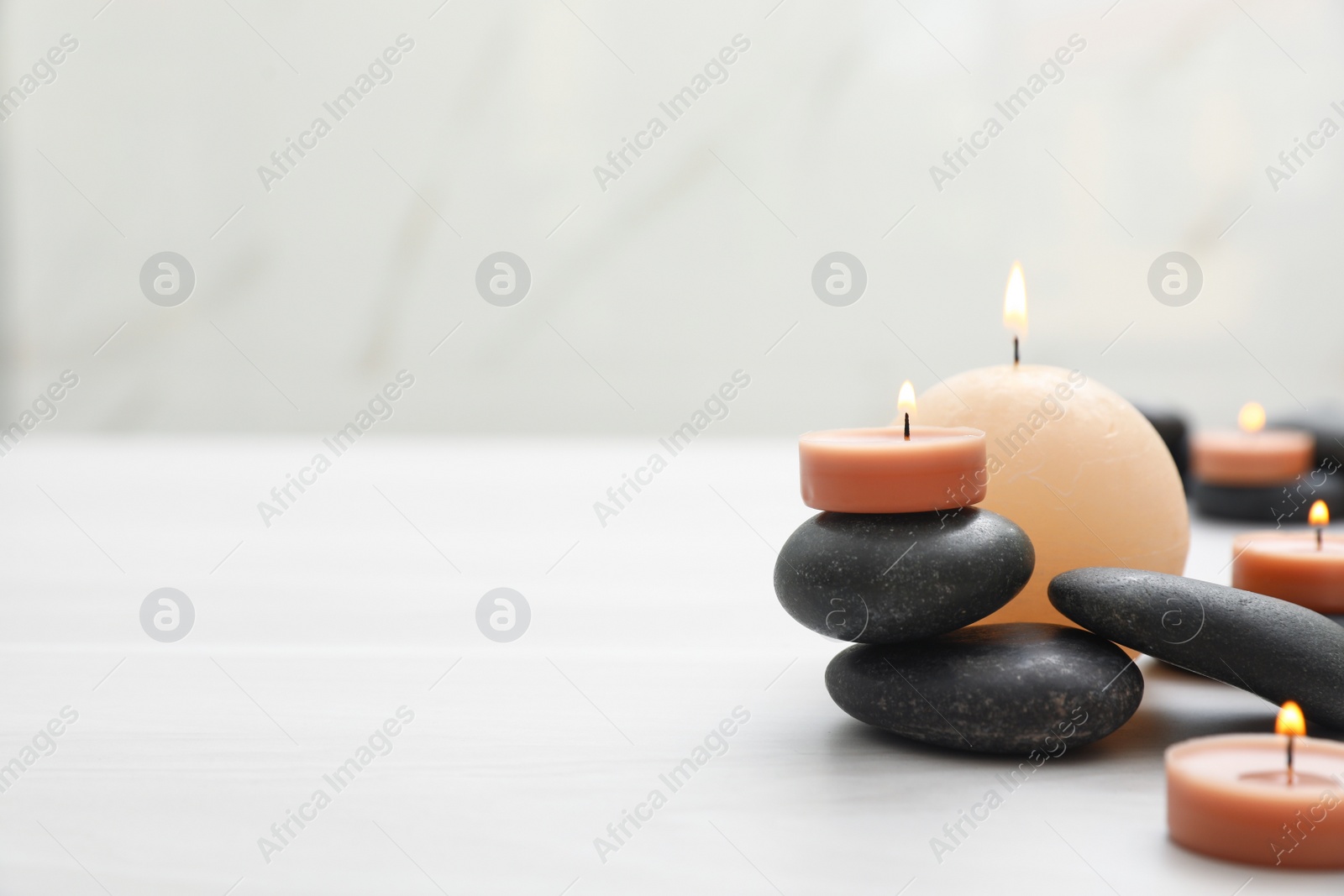 Photo of Composition with spa stones and candles on white table. Space for text