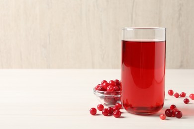 Photo of Tasty cranberry juice in glass and fresh berries on white wooden table, closeup. Space for text