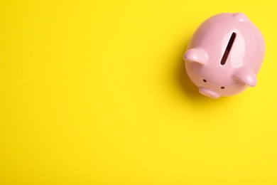 Photo of Top view of piggy bank on yellow background, space for text. Money savings