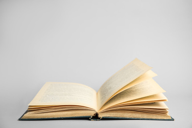 Photo of Open old hardcover book on light grey background. Space for text