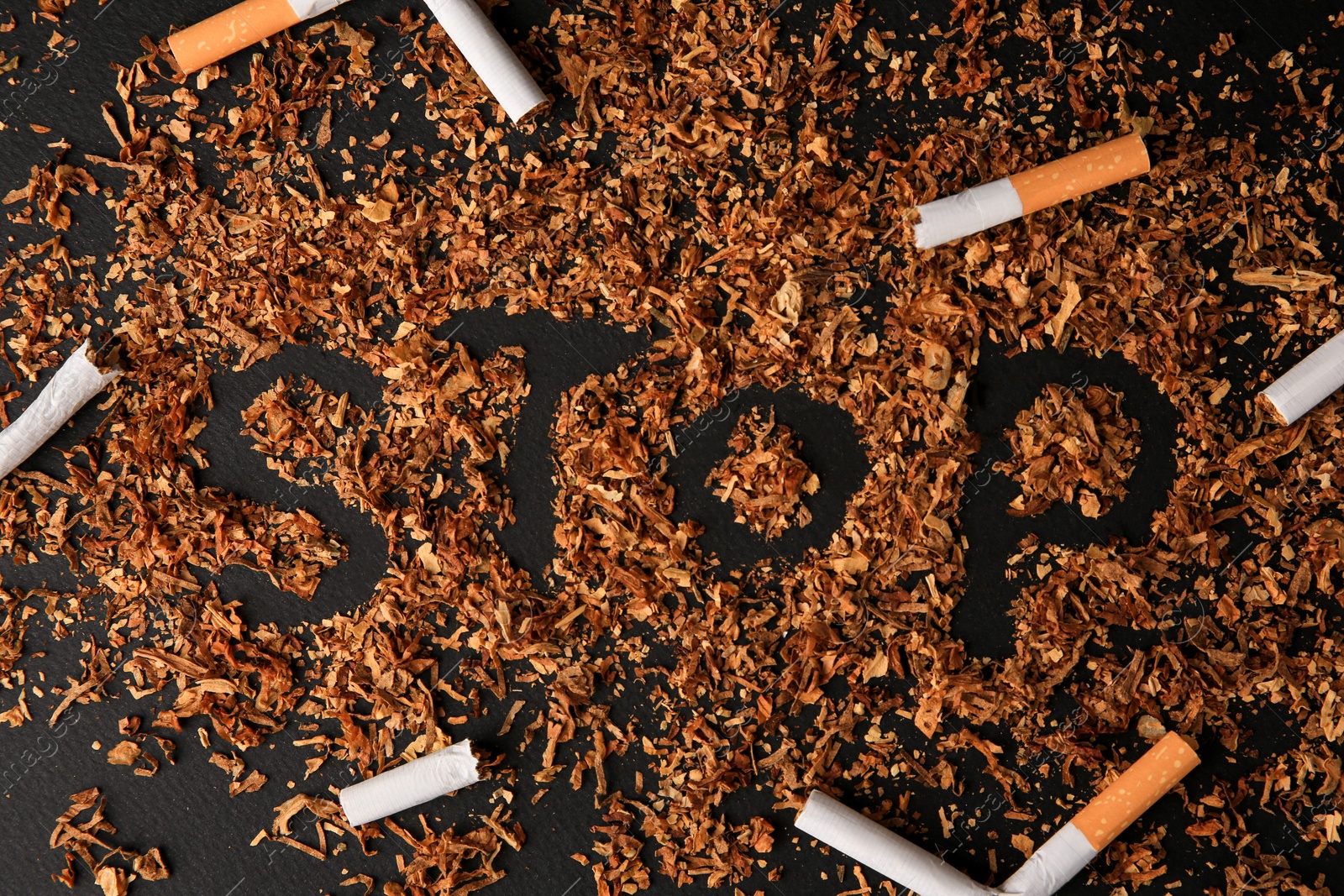 Photo of Word Stop made of dry tobacco and broken cigarettes on dark grey background, flat lay. Quitting smoking concept