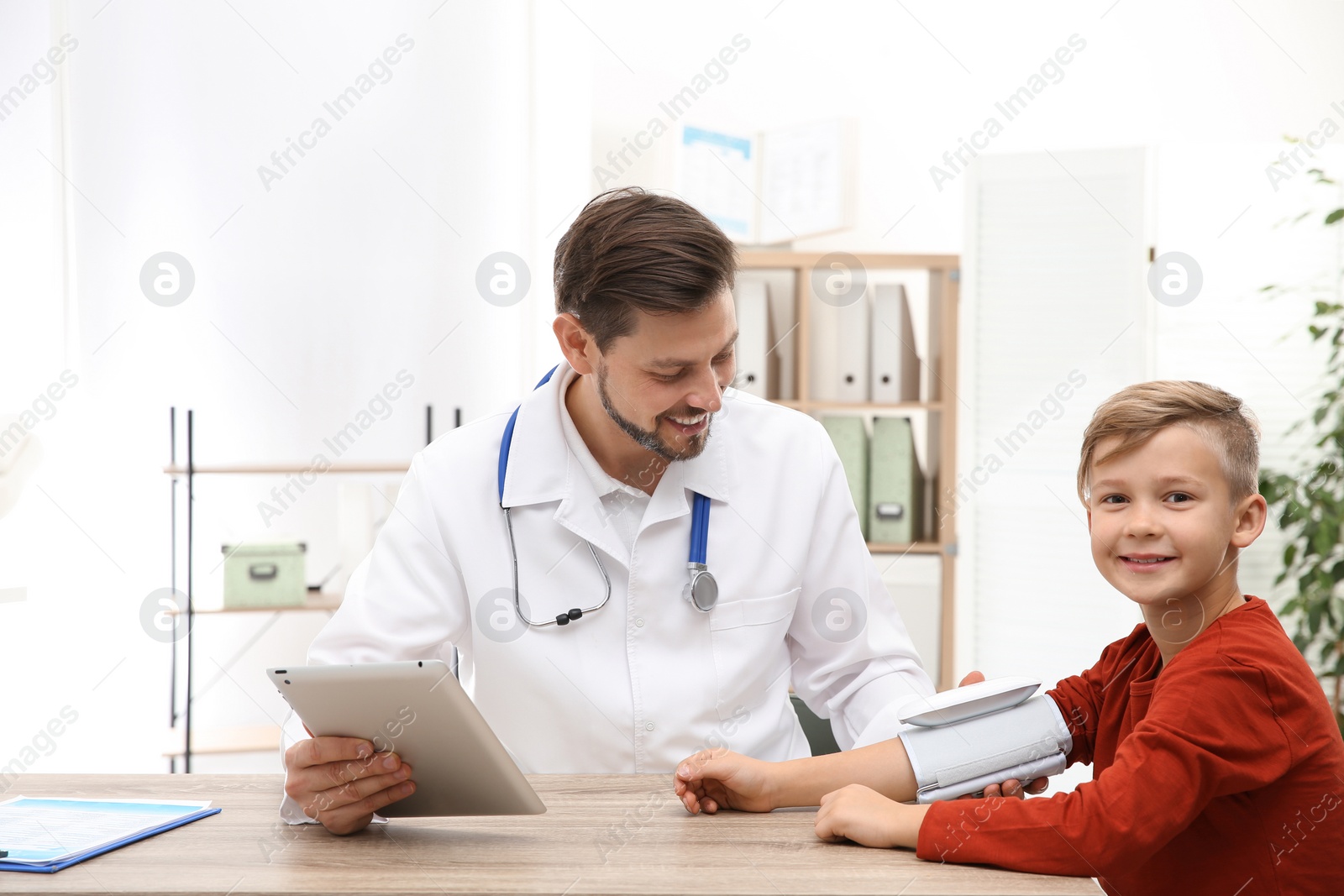 Photo of Doctor checking little boy's pulse with medical device in hospital