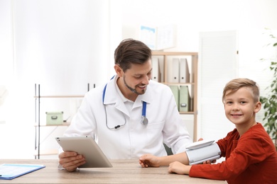 Doctor checking little boy's pulse with medical device in hospital