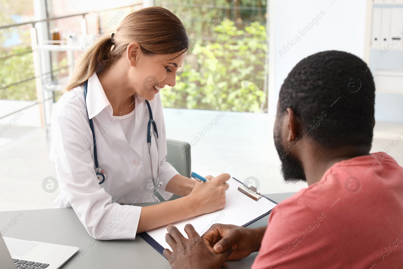 Photo of Young doctor consulting African-American patient in hospital