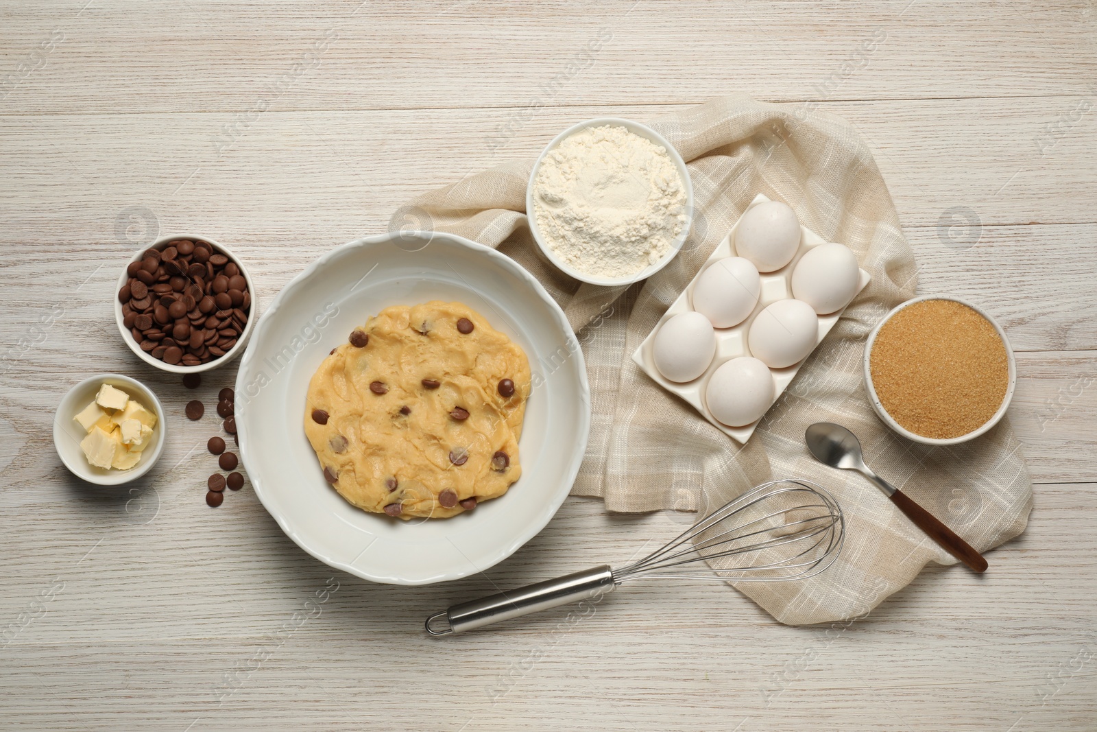 Photo of Fresh dough and different ingredients for cooking chocolate chip cookies on white wooden table, flat lay