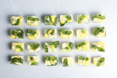 Photo of Ice cubes with mint and lemon on light background, top view