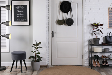 Photo of Hallway interior with stylish furniture, shoes and plants