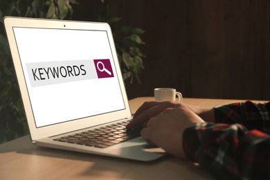 Woman with laptop searching for keywords at table, closeup