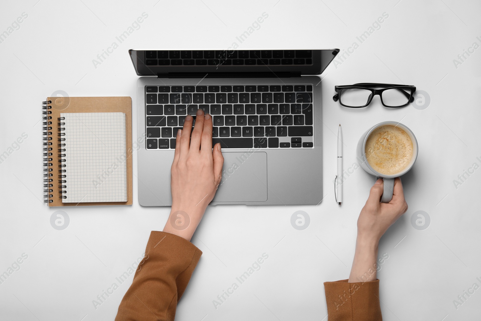 Photo of Woman using laptop at white table, top view