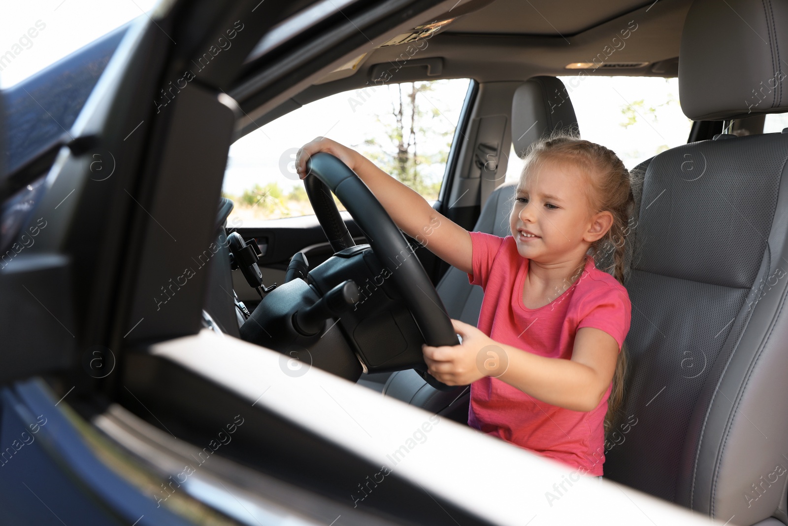 Photo of Little girl playing with steering wheel in car. Family trip