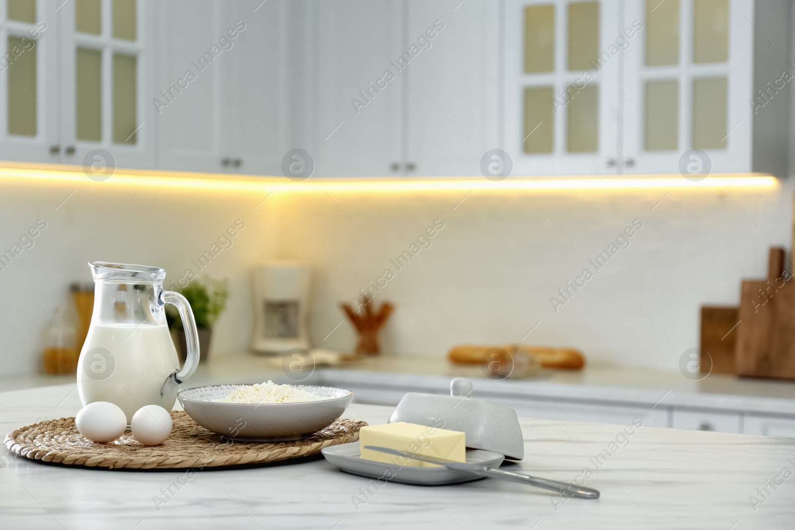 Photo of Different dairy products and eggs on white table in modern kitchen. Space for text