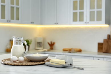 Photo of Different dairy products and eggs on white table in modern kitchen. Space for text