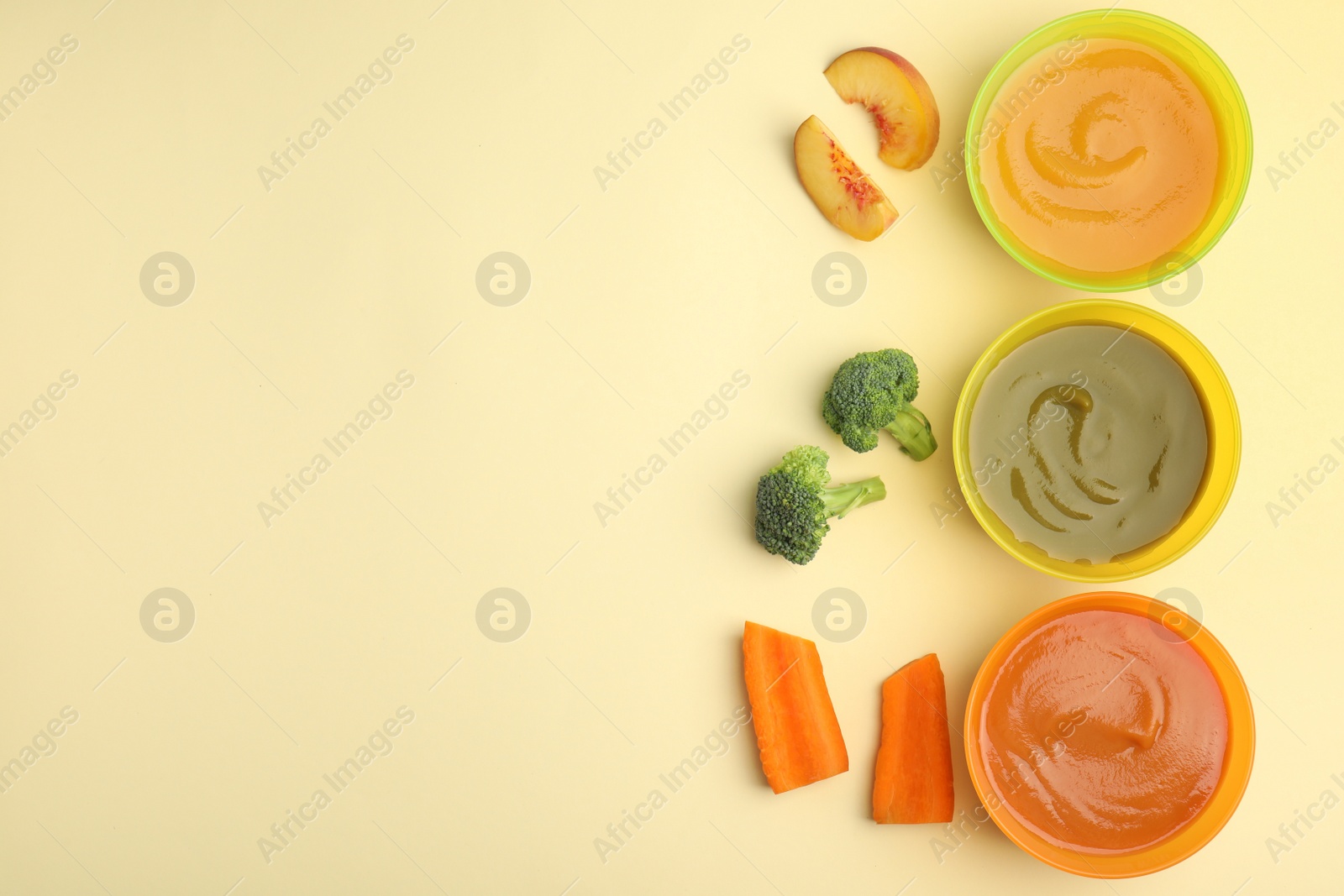 Photo of Baby food in bowls and fresh ingredients on yellow background, flat lay. Space for text