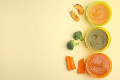 Baby food in bowls and fresh ingredients on yellow background, flat lay. Space for text