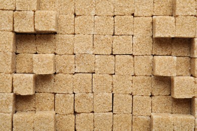 Brown sugar cubes as background, top view