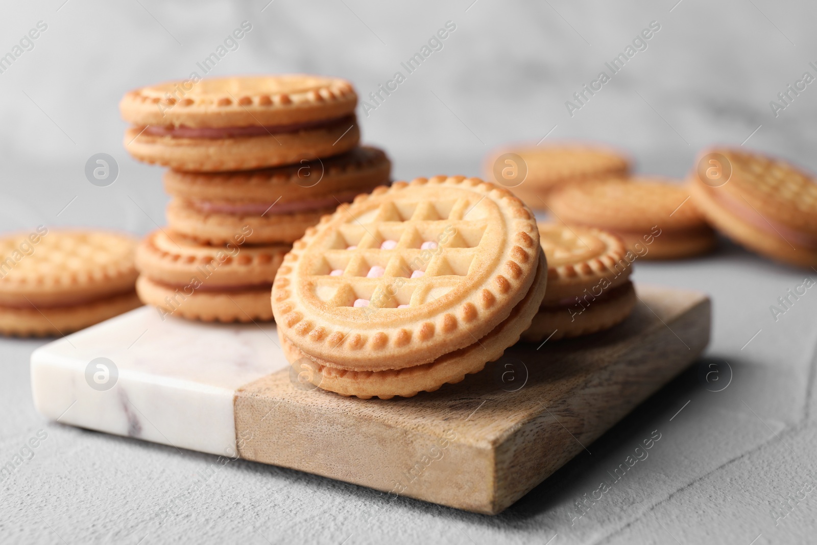 Photo of Tasty sandwich cookies with cream on light grey table, closeup
