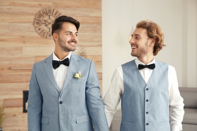 Happy newlywed gay couple in suits at home