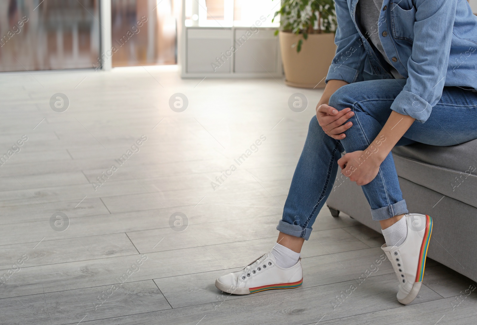 Photo of Young woman suffering from leg pain indoors, closeup with space for text