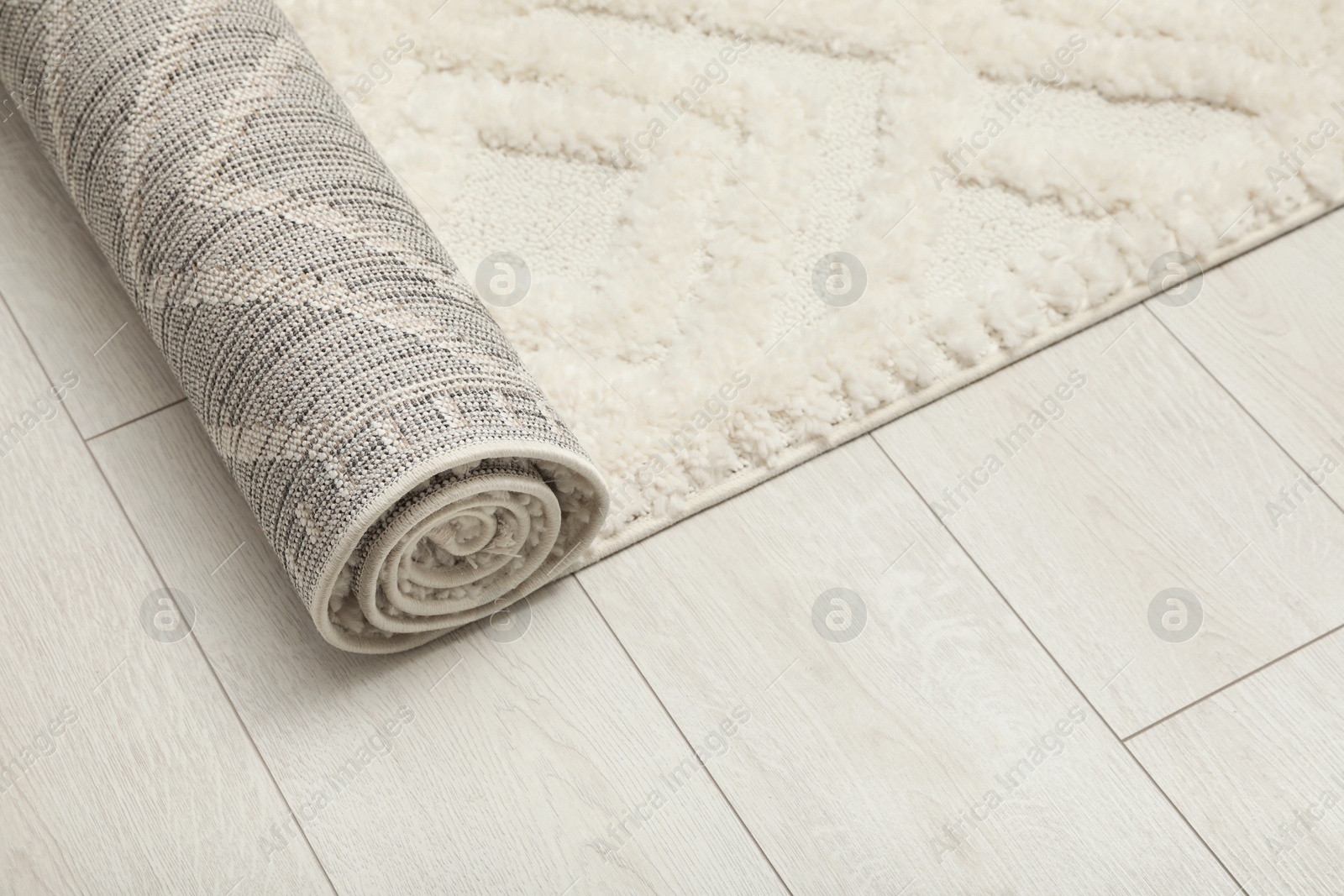 Photo of Rolled white carpet with beautiful pattern on floor, above view. Space for text
