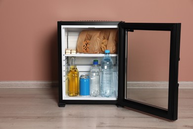 Mini bar filled with food and drinks near pale pink wall indoors