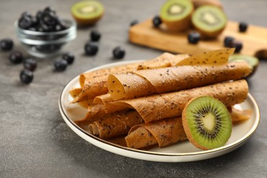 Photo of Delicious fruit leather rolls and kiwi slice on grey table