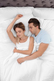 Photo of Young couple sleeping on soft pillows in bed at home