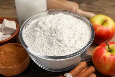 Flour, ripe apples and different ingredients on wooden table, closeup. Cooking yeast cake