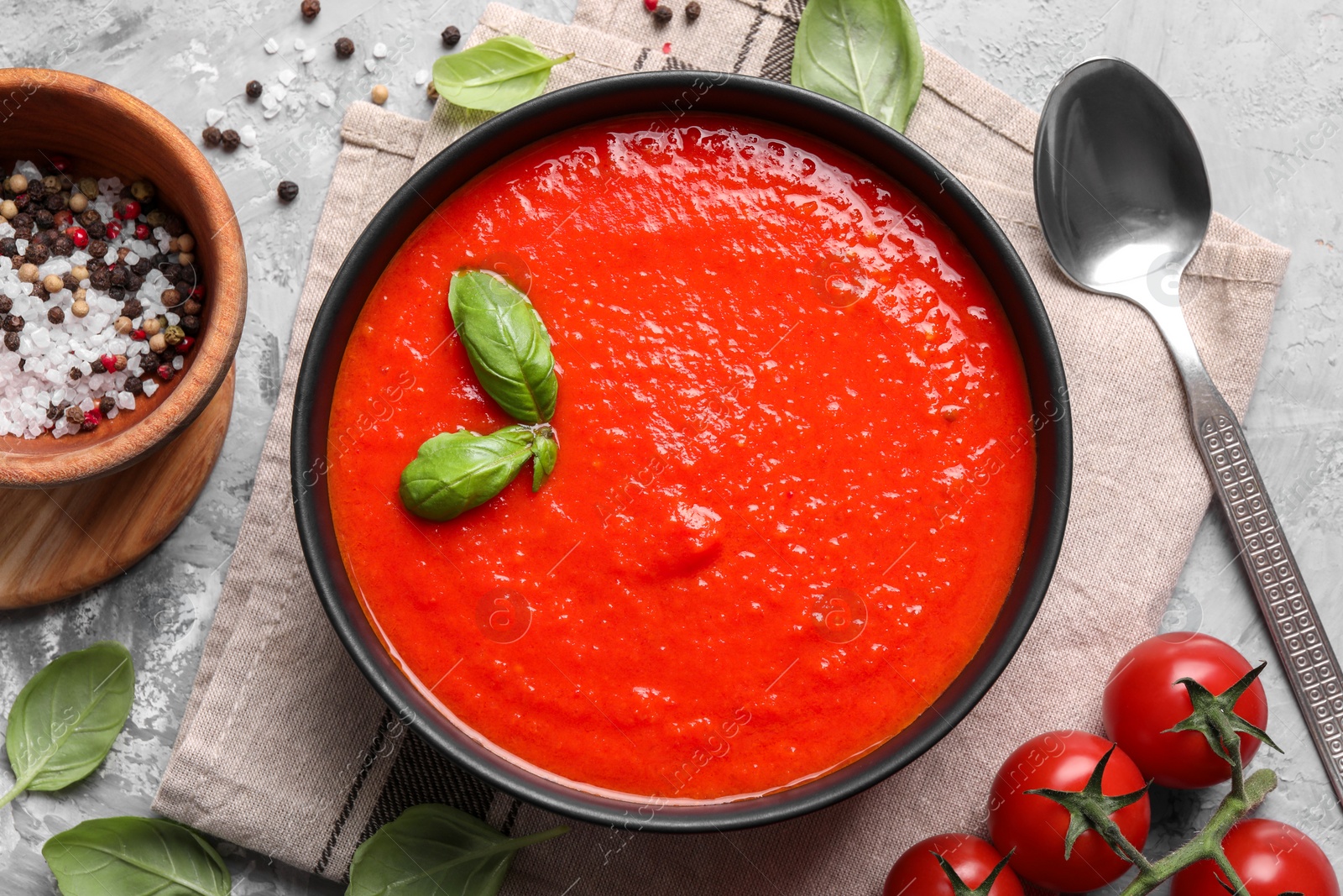 Photo of Delicious tomato cream soup served on grey textured table, flat lay