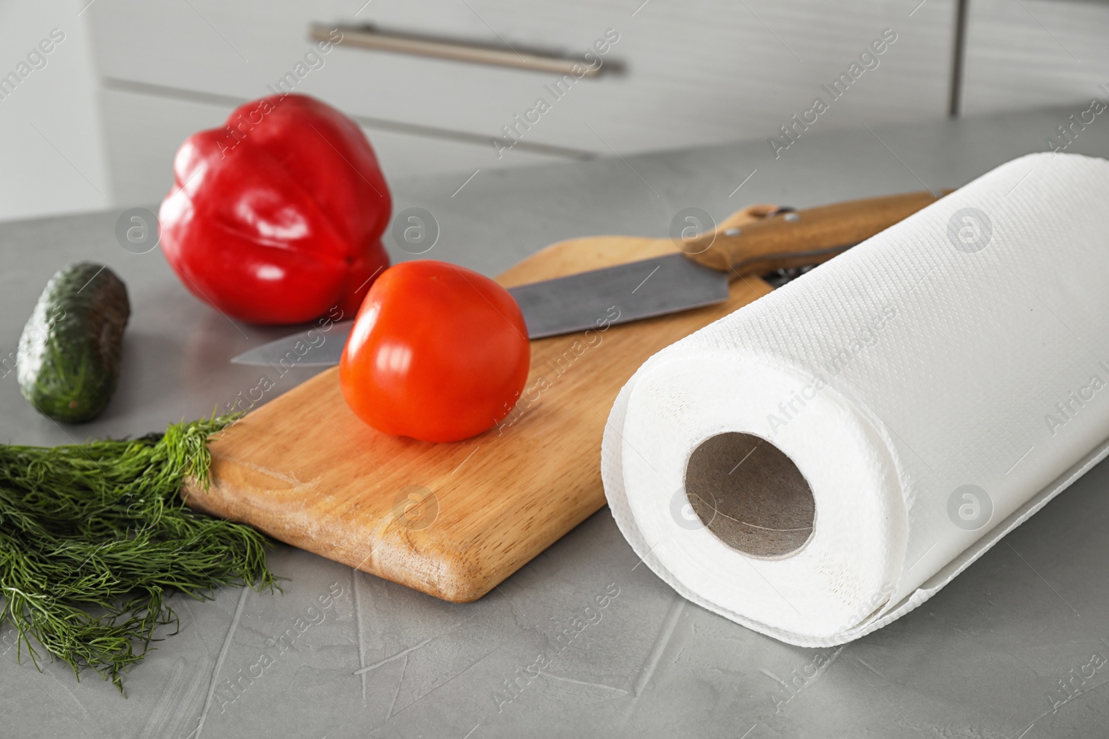 Photo of Paper towels and fresh vegetables on grey table in kitchen