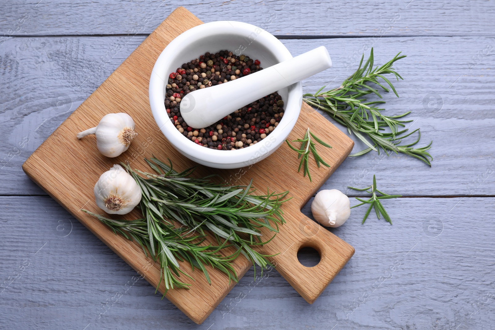 Photo of Fresh rosemary, mortar and garlic on wooden table, flat lay