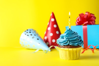 Photo of Delicious birthday cupcake with candle on yellow background, space for text