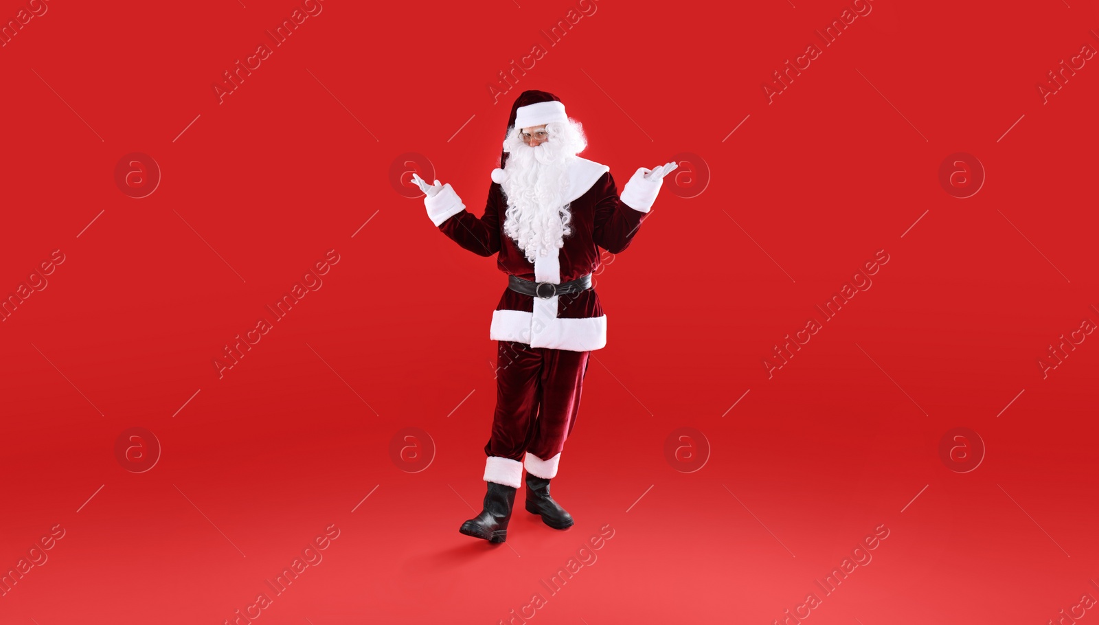 Photo of Full length portrait of Santa Claus on red background