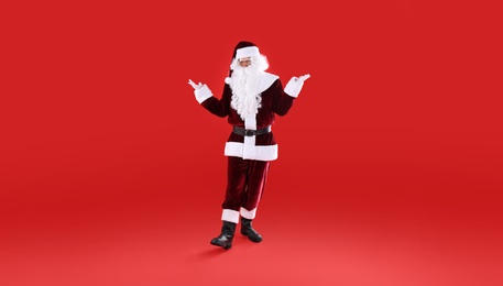 Photo of Full length portrait of Santa Claus on red background