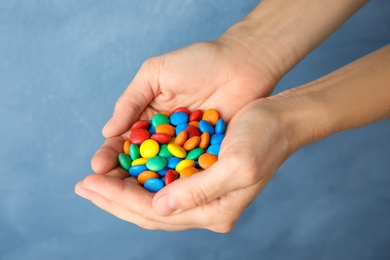 Photo of Woman holding glazed candies on color background, closeup