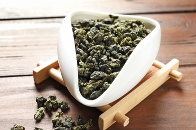 Photo of Chahe with Tie Guan Yin oolong tea leaves on wooden table