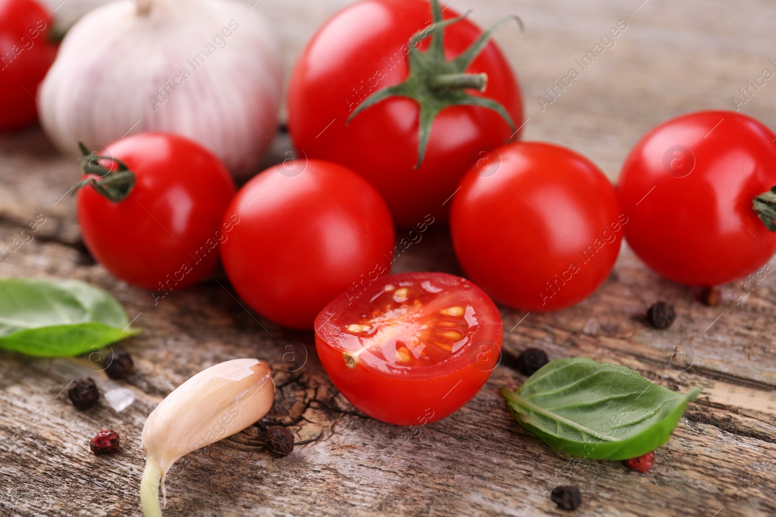 Photo of Ripe tomatoes, basil, garlic and spices on wooden table, closeup